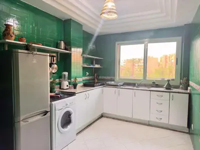 a kitchen with green walls and white cabinets and a dishwasher at cosy terasse apartement in Marrakech