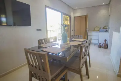 a dining room with a table with chairs and a television at Villa B with a private pool in Oulad Ikhia