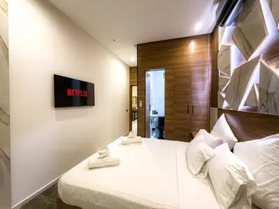 a bedroom with a white bed with a tv on the wall at Séjour chic en ville Jacuzzi privé et Wi-Fi gratuit in Marrakech