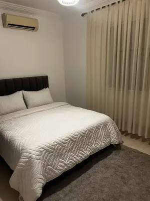 a bedroom with a bed with white sheets and a window at Apartement Mabrouka in Marrakech