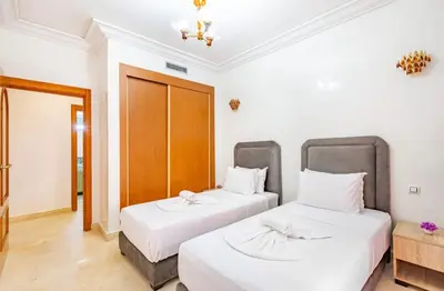 two beds in a room with white walls at AliZ Appartement 2 chambres avec piscine, Majorelle in Marrakech
