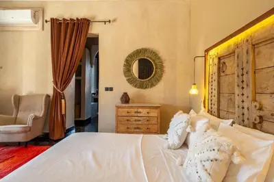 a bedroom with a bed and a chair and a mirror at Villa Chocolat Deluxe in Marrakech