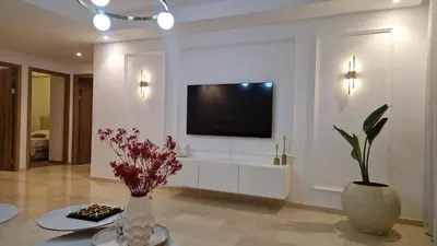 a living room with a television and a vase with flowers at Noria Isli Dar Noor in Marrakech