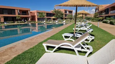 a row of lounge chairs and an umbrella next to a pool at Noria Isli Dar Noor in Marrakech