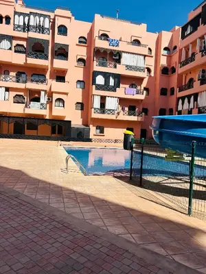 a building with a swimming pool in front of a building at Apparemment première village in Marrakech