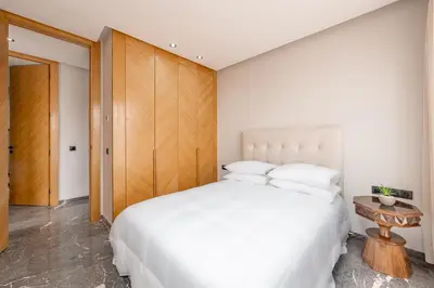 a bedroom with a white bed and a wooden cabinet at 3Br 2Ba Apartment in Marrakech in Marrakech