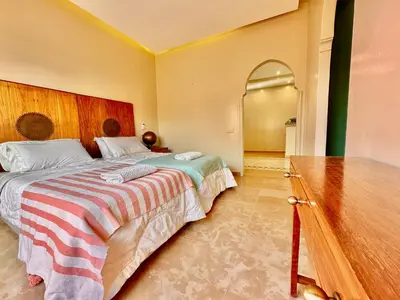 a bedroom with a large bed with a striped blanket at Villa Luxueuse avec Piscine & Vue sur le Golf in Marrakech