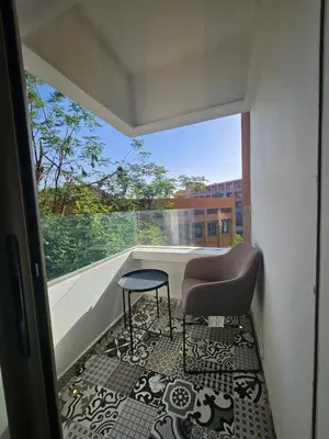a balcony with a chair and a stool and a window at Luxury appartment hivernage in Marrakech