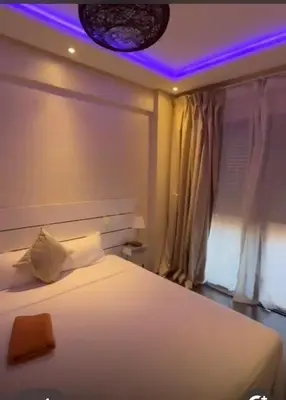 a bedroom with a white bed with a purple lighting at شقة رائعة في جليز خاصة بالعائلات in Marrakech