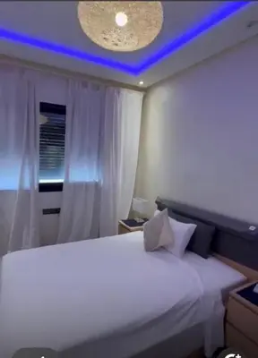 a bedroom with a white bed with a blue light at شقة رائعة في جليز خاصة بالعائلات in Marrakech