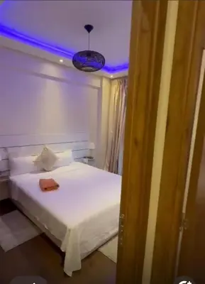 a bedroom with a white bed with a blue light at شقة رائعة في جليز خاصة بالعائلات in Marrakech
