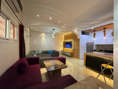 a living room with purple furniture and a kitchen at Résidence touristique Marrakesh in Marrakech