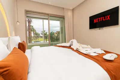 a hotel room with two beds with a tv on the wall at appartement luxe golf prestigia in Marrakech