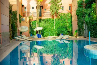 a pool with chairs and umbrellas next to a building at Riad Palm and Pool 2 in Marrakech