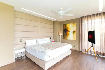 a bedroom with a white bed and a ceiling fan at jacuzzi, 2 pools, luxury villa in Marrakech