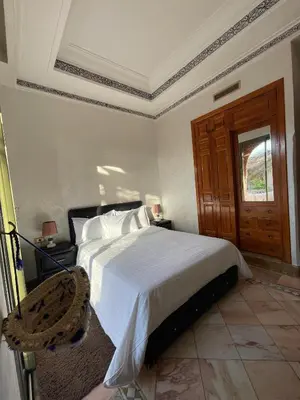 a bedroom with a white bed and a wooden door at Ma kech house in Marrakech
