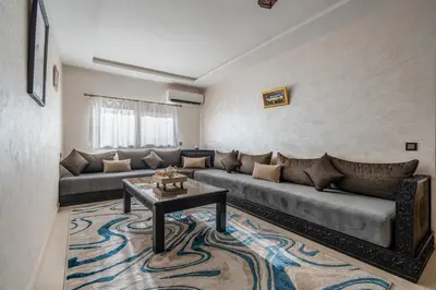 a living room with a couch and a table at Cocon Sable piscine et parking in Marrakech