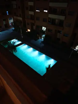 a swimming pool in the middle of a building at night at Cocon Sable piscine et parking in Marrakech