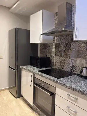 a kitchen with white cabinets and a stainless steel refrigerator at Magnifique appart Moderne 2ch 4pax Tout Confort in Marrakech