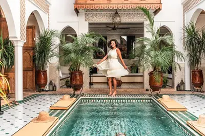 a woman in a white dress standing next to a swimming pool at Marrakech Riads, NL Collection in Marrakech