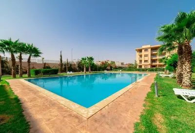 a large swimming pool with palm trees and a building at Prestige de luxe avec piscine in Marrakech