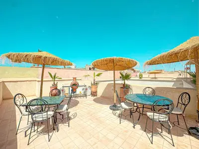 a patio with two tables and chairs and umbrellas at Riad Timija in Marrakech
