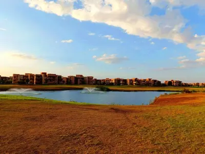 a lake in a field with buildings in the background at Luxury Stay - Prestigia Golf City-3min - Airport in Marrakech