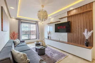 a living room with a couch and a tv on a wall at Studio Haut de Gamme in Marrakech