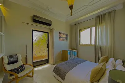 a bedroom with a bed and a chair and a window at Villa luxueuse marrakech in Marrakech