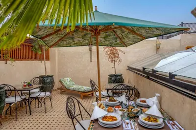 a patio with tables and chairs and an umbrella at Riad AL-Ghazlan Hamam & Spa in Marrakech