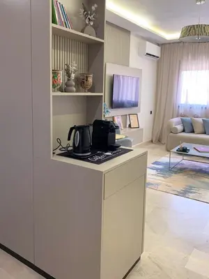 a white kitchen with a counter and a living room at Nejma House - 1 BR with pool in Marrakech