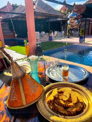 a table with a plate of food next to a pool at FERME D'HOTES BARGHALi in Marrakech