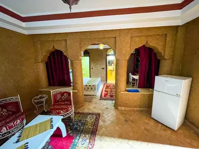 a living room with a white refrigerator and chairs at FERME D'HOTES BARGHALi in Marrakech