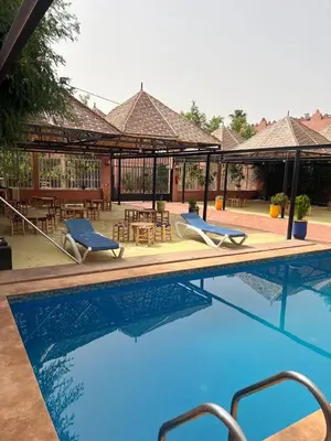 a large swimming pool with chairs and a patio at FERME D'HOTES BARGHALi in Marrakech