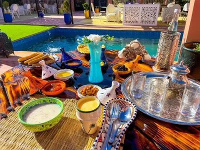 a table with plates of food next to a swimming pool at FERME D'HOTES BARGHALi in Marrakech