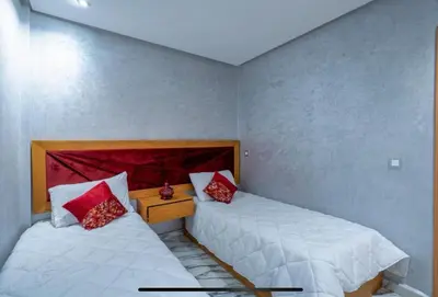two beds in a small room with red pillows at Gone app Marrakech in Marrakech