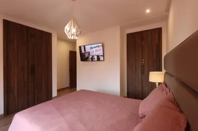 a bedroom with a pink bed and a tv at Modern top floor apartment with balcony! in Marrakech