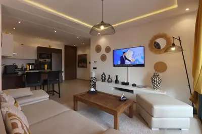 a living room with a couch and a tv on a wall at Modern top floor apartment with balcony! in Marrakech