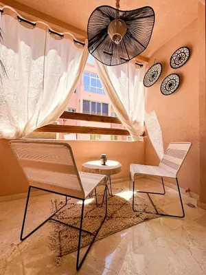 a room with two chairs and a table and a fan at Stylish Escape Modern Comforts in Marrakech