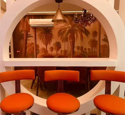 a bar with orange stools and a mural of palm trees at Triplex luxe marrakech in Marrakech