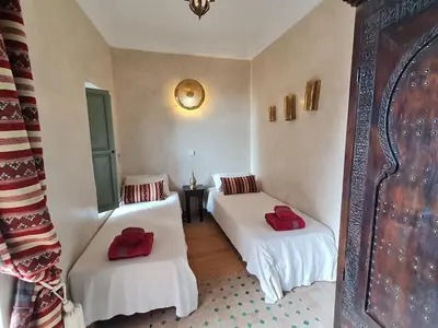 two beds in a room with red pillows on them at Riad Bouchra, riad privatif proche de la place Jemaa-El-Fna in Marrakech