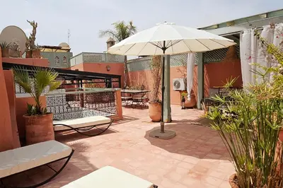 a patio with an umbrella and chairs and tables at Riad Bouchra, riad privatif proche de la place Jemaa-El-Fna in Marrakech