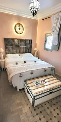 a bedroom with a large white bed with a table at Riad Bouchra, riad privatif proche de la place Jemaa-El-Fna in Marrakech