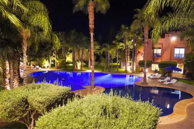 a swimming pool with palm trees and a hotel at Riador in Marrakech