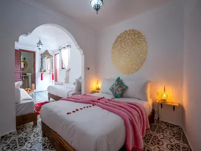 a bedroom with a large bed with a pink blanket at Riad Loriental And Spa in Marrakech