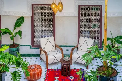 two chairs and a table in a room with plants at Riad les palmiers de la medina in Marrakech