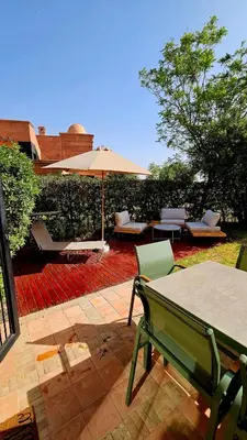 a patio with a table and an umbrella and chairs at Votre Villa Soleil et Chaleureuse in Marrakech