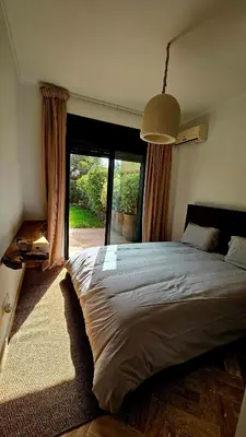 a bedroom with a large bed and a large window at Votre Villa Soleil et Chaleureuse in Marrakech