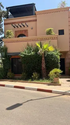 a building with a palm tree in front of a street at Votre Villa Soleil et Chaleureuse in Marrakech