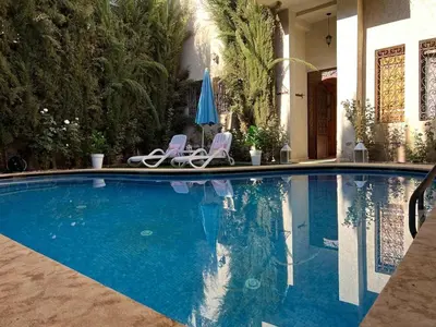 a swimming pool with two chairs and an umbrella at Villa in Marrakesh Targa with swimmingpool in Marrakech